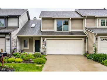 Inviting home featuring a two-car garage, manicured lawn, and charming landscaping at 2949 River Bay N Dr, Indianapolis, IN 46240