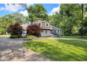 Charming house with red door, brick, dormer windows, and lush landscaping at 5506 Kessler Blvd N Dr, Indianapolis, IN 46228