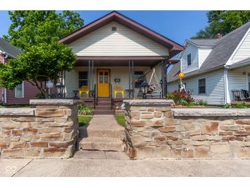 Charming single-story home featuring a welcoming front porch, stone retaining wall and well-manicured landscaping at 60 S 8Th Ave, Beech Grove, IN 46107