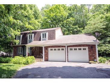 Charming brick home with a two-car garage and a well-manicured lawn surrounded by lush trees at 7115 Fremont Ct, Indianapolis, IN 46256