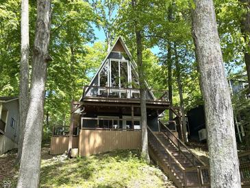 A-frame home with a wraparound deck surrounded by beautiful trees and lush foliage at 7207 Grouper Dr, Nineveh, IN 46164