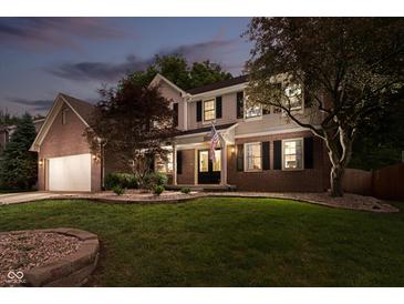 Charming two-story home with a brick and siding exterior, lush lawn, and an American flag at 10243 Brixton Ln, Fishers, IN 46037