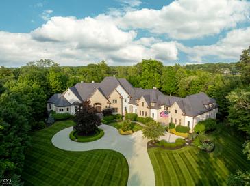Stunning aerial view of a luxury home featuring manicured lawns, a circular driveway, and mature trees at 11101 Hawthorn Rdg, Fishers, IN 46037