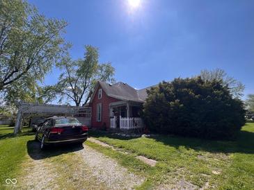 Charming red home with a white picket fence, a gravel driveway, and a well-maintained lawn at 2115 S I St, Elwood, IN 46036
