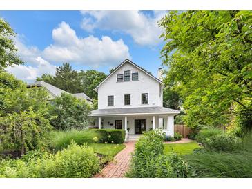 Charming white two-story home with a landscaped front yard and inviting brick walkway under a sunny, partly cloudy sky at 3215 N Pennsylvania St, Indianapolis, IN 46205