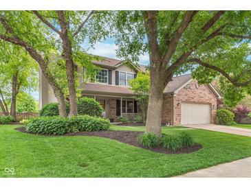 Charming two-story home with well-manicured lawn, mature trees, and brick accents at 10673 Misty Hollow Ln, Fishers, IN 46038