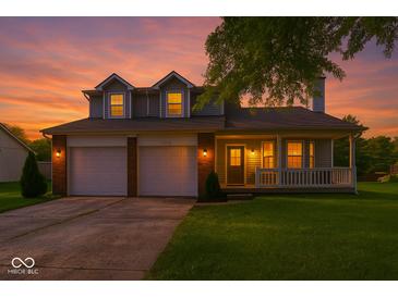 Charming two-story home featuring a front porch, attached two-car garage, and well-manicured lawn at sunset at 11612 E 75Th St, Indianapolis, IN 46236