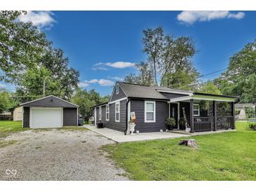 Charming home featuring a detached garage, well-kept lawn, and a welcoming front porch at 1617 S Whittier Pl, Indianapolis, IN 46203