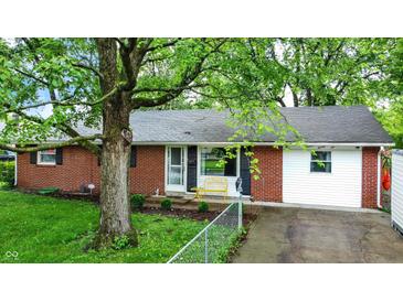 Charming one-story home featuring a brick facade, a well-manicured lawn, and mature trees providing ample shade at 1926 Fairmont Ct, Indianapolis, IN 46229