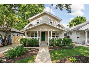 Charming two-story home with a welcoming front porch, lush landscaping, and a vibrant green front door at 4818 Winthrop Ave, Indianapolis, IN 46205