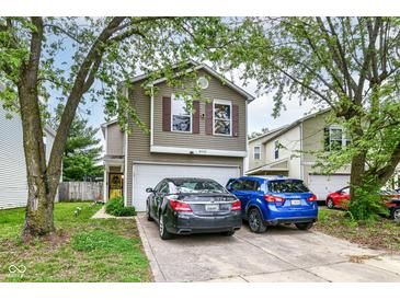 Two-story home with tan siding, dark shutters, and a two-car garage, plus driveway parking at 6553 Black Antler Dr, Indianapolis, IN 46217