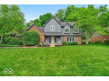 Charming two-story home featuring a well-manicured lawn, beautiful landscaping, and a welcoming front porch at 12961 Limberlost Dr, Carmel, IN 46033