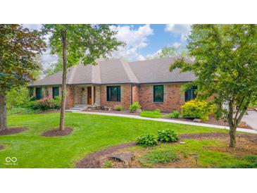 A well-maintained brick home featuring a stone accent, lush lawn, and mature landscaping in a tranquil setting at 1633 W 200 North, Greenfield, IN 46140