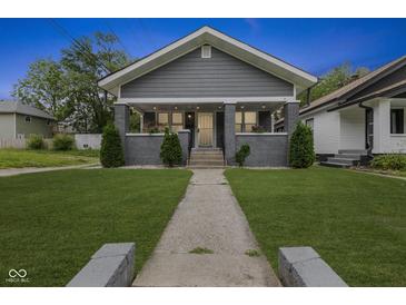 Charming single-story home featuring a manicured front yard with an inviting walkway and covered porch at 441 N Temple Ave, Indianapolis, IN 46201