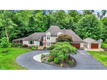 Stunning two-story home with a circular driveway, mature trees, and an American flag at 4623 E Windsor Ln, Columbus, IN 47201
