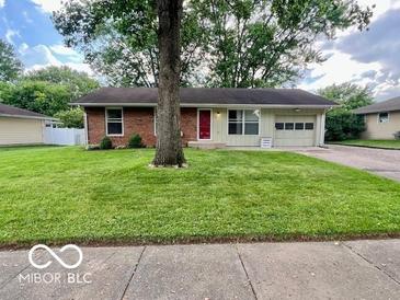 Charming single-story home featuring a red door, attached garage, and a lush green lawn at 1834 Chandler Ln, Columbus, IN 47203