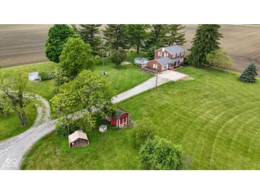 Expansive aerial view of a red brick two-story home surrounded by lush green lawns, mature trees and outbuildings at 4817 N 150 W, Anderson, IN 46011