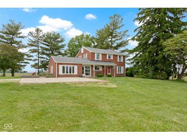 Two-story brick home with an expansive lawn, mature trees, and red front door offers classic charm and curb appeal at 4817 N 150 W, Anderson, IN 46011