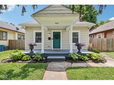 Charming home featuring a covered front porch with vibrant plants and a freshly painted teal front door at 923 42Nd St, Indianapolis, IN 46205