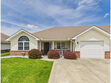 Charming ranch home featuring a manicured lawn, covered porch and attached garage at 1108 Northfield Ln, Anderson, IN 46011