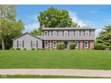 Traditional two-story home with gray siding, brick accents, manicured lawn, and mature trees at 12112 Roxbury Pl, Carmel, IN 46033