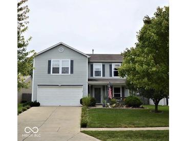 Charming two-story home with well-manicured lawn, attached garage and an inviting front porch with an American flag at 2210 Bridlewood Dr, Franklin, IN 46131