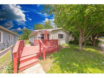 Charming home featuring a red deck and lush green yard with mature trees at 3220 Newton Ave, Indianapolis, IN 46201