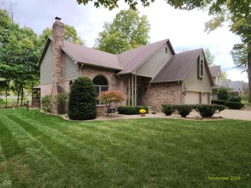 Charming two-story home with brick facade, attached two-car garage and manicured front lawn at 3819 S Village Dr, New Palestine, IN 46163