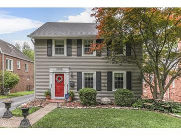 Charming two-story home featuring a red front door, black shutters, and a well-manicured lawn at 5306 N Kenwood Ave, Indianapolis, IN 46208
