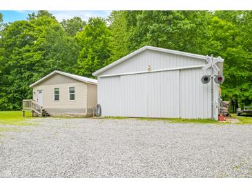 Side exterior view of the vinyl sided home and metal outbuilding, with a graveled parking area at 5858 N West Shore Dr, Morgantown, IN 46160