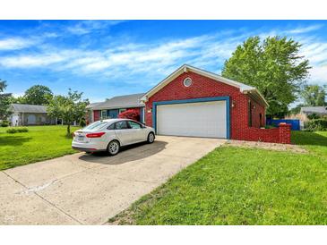 View of a red brick home with attached garage, driveway, and lush green lawn under a bright blue sky at 602 Pioneer Dr, Indianapolis, IN 46217