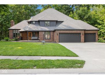 Charming brick home boasts a well-manicured lawn and three-car garage, nestled among mature trees at 6350 Red Oak Dr, Avon, IN 46123