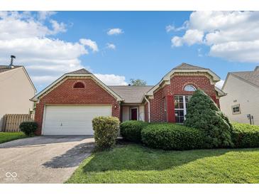 Charming brick home featuring a two-car garage, landscaped yard, and eye-catching architectural details at 69 Stoneybrook Dr, Greenwood, IN 46142
