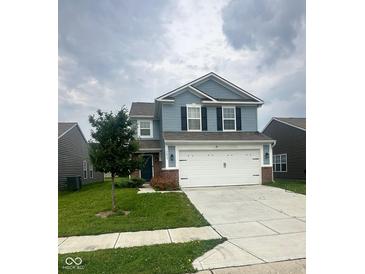 Charming two-story home with a two-car garage, tree in the front yard, and light blue siding at 10835 Spirit Dr, Ingalls, IN 46048