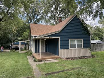 Charming blue home featuring a covered porch and well-maintained lawn surrounded by mature trees at 1206 Mcdougal St, Indianapolis, IN 46203