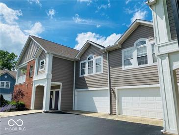 Beautiful townhome featuring a two-car garage, gray siding and a well-manicured lawn underneath a bright blue sky at 1280 Shadow Ridge Rd, Indianapolis, IN 46280