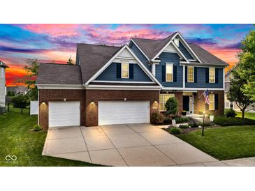 Beautiful two-story home featuring a three-car garage and well-manicured lawn at dusk at 13766 Heatherfield Dr, Fishers, IN 46038