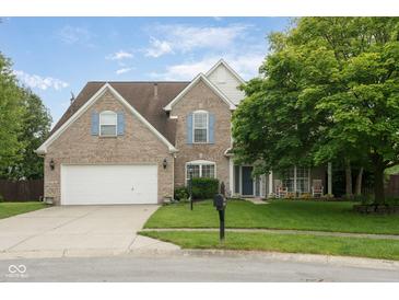 Charming two-story brick home featuring an attached two-car garage and a cozy front porch, set on a well-manicured lawn at 15409 Heath Cir, Westfield, IN 46074