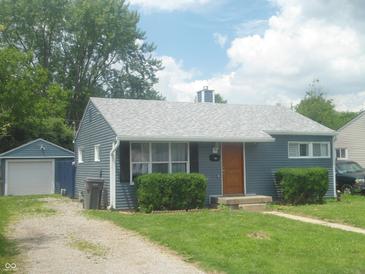 Charming single-story home with blue siding, mature landscaping, and detached garage at , Indianapolis, IN 46218