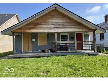 Modest single-story home with a covered porch, gray siding and some boarded-up windows at 1844 E Minnesota St, Indianapolis, IN 46203