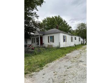 Exterior of a white single-story home with a red front door, weathered siding, and a gravel driveway at 2627 Lincoln St, Anderson, IN 46016
