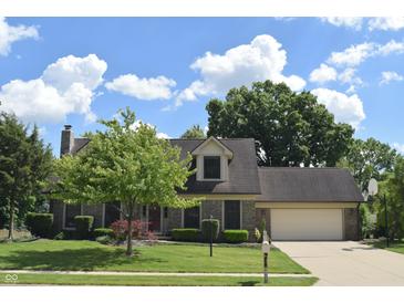 Well-maintained two-story home with lush lawn, mature trees, brick facade, attached garage and basketball hoop at 1065 Lakewood South Dr, Brownsburg, IN 46112