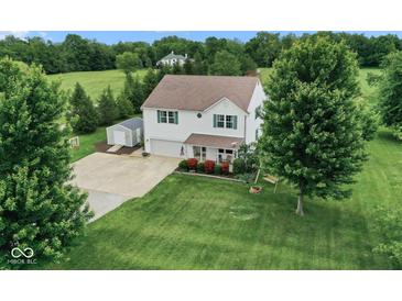A charming two-story home, a lush green lawn, mature trees, storage shed, and basketball hoop at 11198 N 650 W, Fountaintown, IN 46130