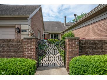 Charming brick home featuring a decorative iron gate and lush green landscaping at 131 Olde Mill Bay, Indianapolis, IN 46260