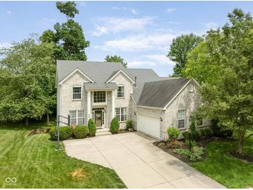 Beautiful two-story home featuring a brick facade, attached garage, and well-manicured landscaping on a sunny day at 13861 Barberry Ct, Carmel, IN 46033