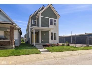 Charming two-story home featuring a welcoming porch, a well-manicured lawn, and fresh flowers at 1405 Deloss St, Indianapolis, IN 46201