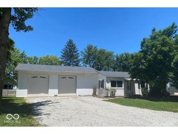 Charming single-story home featuring a two-car garage, gravel driveway, and well-maintained lawn against a bright blue sky at 1882 Knox Dr, Clayton, IN 46118