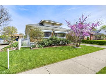 Charming single-Gathering home featuring a well-manicured lawn, sidewalk, and mature landscaping on a sunny day at 1641 Winton Ave, Speedway, IN 46224