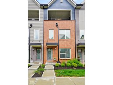 Charming townhome boasts red brick facade, modern design, inviting curb appeal, and balcony at 2125 Coretta Way, Indianapolis, IN 46202