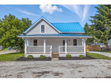 Charming home with a blue metal roof and welcoming front porch, set against a bright blue sky at 300 N Church St, Arcadia, IN 46030